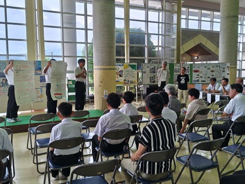 地元中学生の発表をサポートする㈱アイシン後藤氏と㈱ユニックの竹内氏