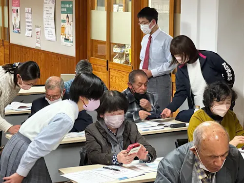 デジタル部の中学生が、地域の方にスマートフォンの使い方をサポートしています