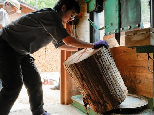 樽丸工房で働く野一色さん。師匠は来客人と談笑しつつ、気にかけてくれています。