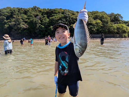 漁業体験ツアー造成事業の建干網漁で鯛を手にし笑顔を見せる子ども