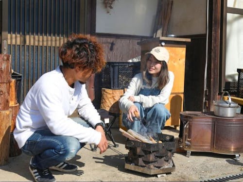 暖を取りながら、奥様と談笑する西村さん