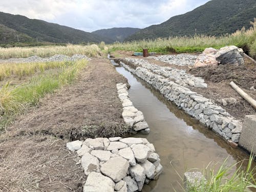 鬱蒼と雑草が茂っていた排水路が石積みで生まれ変わりつつあります