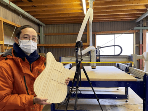 奥にみえる、木工用CNCルーター「ShopBot」で、制作中のギターを手にOneShot!