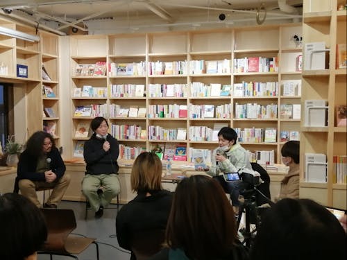 「みんなでつくるみんなの本屋 SEESAWBOOKS」でイベントを行う様子。後ろの本棚にはぎっしりと本が並んでいる。