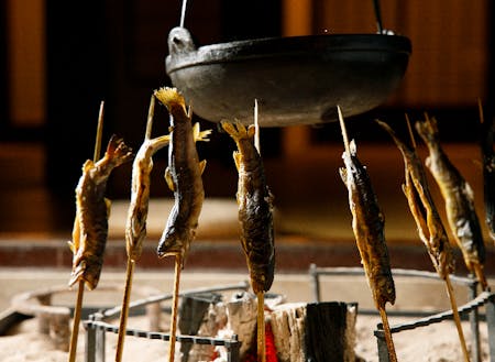 囲炉裏で川魚や鍋を調理する時間で集落住民と観光客が交わります