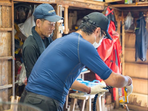 初心者漁師にロープワークを指導する先輩漁師