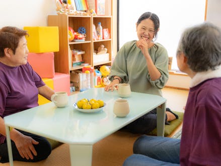 子育てサークルを手伝ってくださる地域の方と談笑中の平井さん。