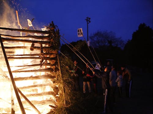 鬼火焚きに書初めの習字紙をかざす様子。高く舞い上がるとよいことが。