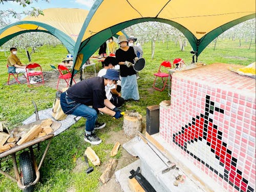 りんご園地で様々な遊びをつくっている住民団体「ふじさきAPPLEミアミューズメント」によるりんごのお花見会。りんごの花に囲まれながら手作りアップルパイなどを提供。