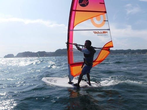 マリンアクティビティをきっかけに鎌倉リピーターになり、2年前に鎌倉移住をしたYさん。「今では会社の知り合いより、鎌倉の知り合いが多くなりました。年齢、性別、国籍を超えた自慢の友人達です。」と鎌倉移住によるコミュニティの変化を語ってくれた。写真は、多くの友人ができるきっかけになったというウィンドサーフィンの様子。