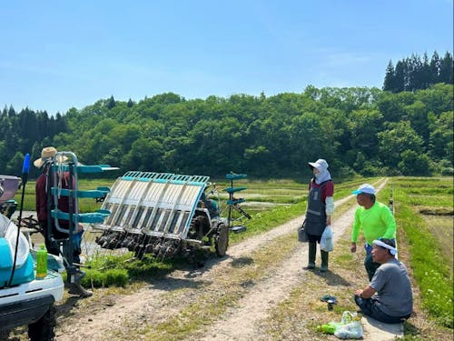 田植え作業の休憩の様子。飲み物やお茶菓子を持ち寄り世間話をする時間でもあります