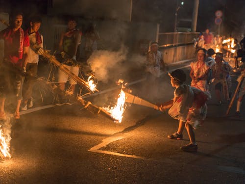 行列に地元の子供たちが割って入り、松明の火が燃え過ぎないようバンバラ竹でに力いっぱいたたく!