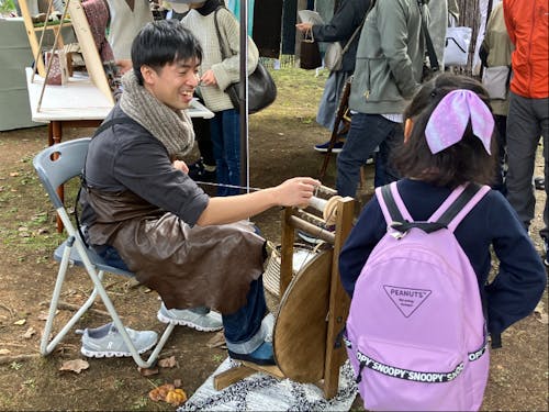 糸車で羊毛を紡いでいる猪又さん