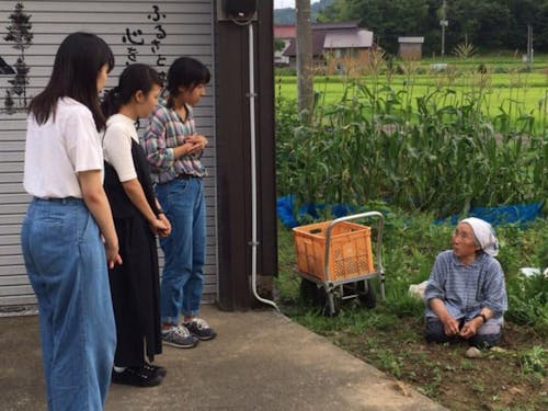 畑で作業をしているお母さんに話を聞く村・留学参加者