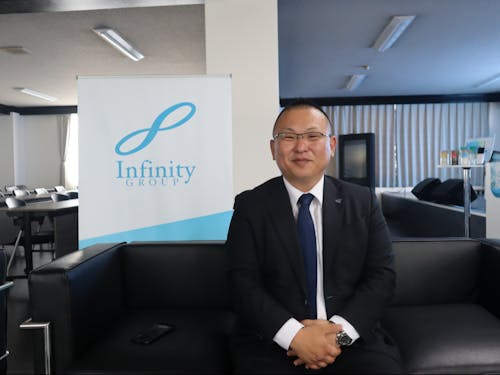 上森社長とインフィニティグループのロゴ