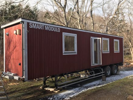 冬に設置した移動可能な木造建築”Smart Modulo”。宿泊や飲食もできるテレワーク拠点として利用可能。ここに太陽光発電システムやウッドデッキ等を整備していく。断熱がしっかりとしていて、冬の森の中でも快適に過ごすことができた。