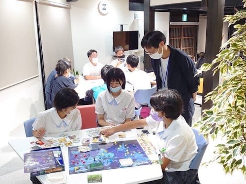 目の前にあるワーケーション施設で高校生と塾スタッフはボードゲーム、後ろでは大人が何かのミーティング